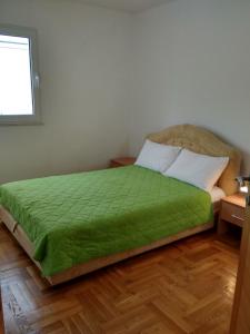a bedroom with a bed with a green comforter at Apartments Charme in Bečići
