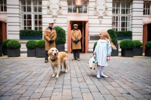 a little girl and a dog in front of a building at Rosewood London in London