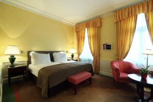 a hotel room with a bed, chair, lamps and a window at Le Palais Art Hotel Prague in Prague