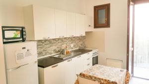 cocina con armarios blancos, fregadero y nevera en Le Case di Giorgia, en San Vito lo Capo