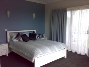 um quarto com uma cama com paredes azuis e uma janela em Swan Lake Guest House em Ventnor