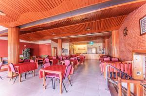 a dining room with red chairs and tables and a brick wall at Hotel Silvia in Empuriabrava