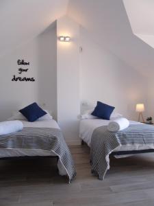 ベナルマデナにあるBenalHoliday Sun & Seaの白い壁の客室で、ベッド2台、青い枕が備わります。
