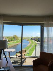 a room with a large window with a view of a river at Nordseehotel Benser Hof am Hafen in Bensersiel