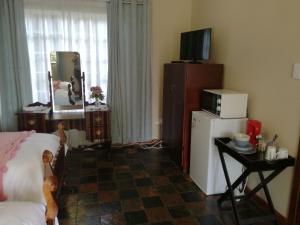 a room with a bed and a television and a refrigerator at Cadle House in Vryheid