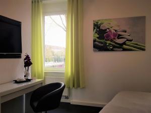 a room with a bed and a window with yellow curtains at Hotel & Restaurant Schützen in Rastatt