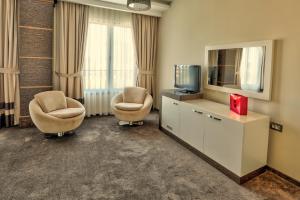 a living room with two chairs and a television at Amazona Hotel in Prishtinë