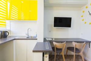 基輔的住宿－Комфортные мини-апартаменты студио на Ломоносова，厨房配有黄色橱柜、水槽和2把椅子