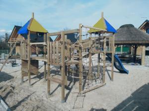 a wooden playground with a slide in the sand at Bacówki nad jeziorem Goszcza in Lubrza