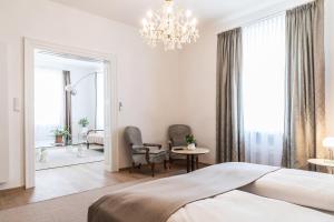 a bedroom with a bed and a chandelier at Sandwirth Suites Palais Musil in Klagenfurt