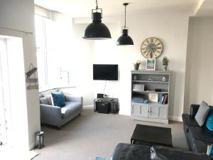 sala de estar con sofá y reloj en la pared en Wight view, flat 2 rosslyn house, en Swanage