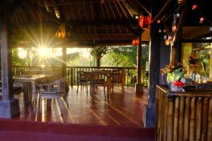 a restaurant with tables and chairs and the sun shining at Prashanti Bali in Ubud