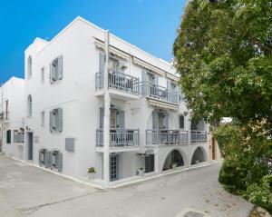 ein weißes Gebäude mit Balkonen und einem Baum in der Unterkunft Golden Beach Studios Down Town in Naxos Chora