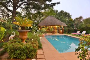 a swimming pool with a gazebo and a house at Bellgrove Guest House Sandton in Johannesburg