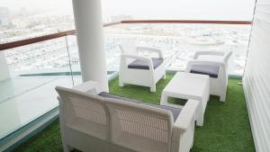 a balcony with white chairs and tables and a view of a harbor at Marina Towers - Herzeliya in Herzelia 