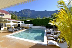 a swimming pool with lounge chairs and a house at Hotel Le Cilaos in Cilaos