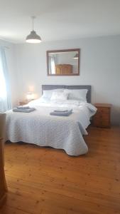 um quarto com uma cama com lençóis brancos e um espelho em Spindrift em Moville