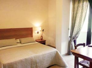 Schlafzimmer mit einem Bett, einem Tisch und einem Fenster in der Unterkunft Albergo Villa Riccio in Itri