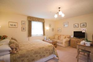 a bedroom with a bed and a couch and a television at Park Cottage in Warwick