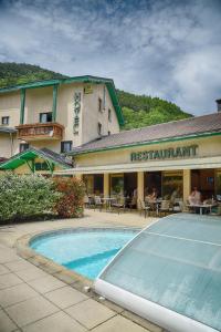 a resort with a swimming pool in front of a restaurant at Logis Murtel in La Mure
