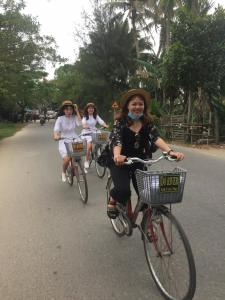 a group of women riding bikes down a street at Do River Homestay in Hoi An