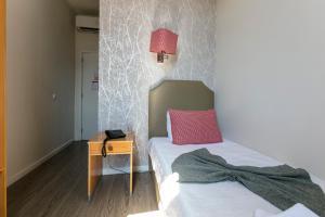 a bedroom with a bed with a pink pillow and a table at Guest House Porto Clerigus in Porto