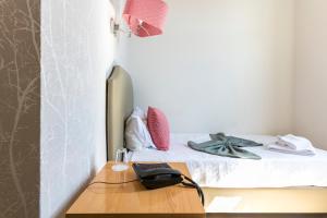 a small bedroom with a bed with a desk and a laptop at Guest House Porto Clerigus in Porto
