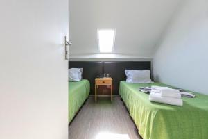 a bedroom with two beds with green sheets and a cross at Guest House Porto Clerigus in Porto