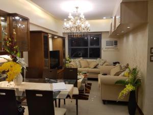 ein Wohnzimmer mit Sofas und einem Kronleuchter in der Unterkunft KC 2-Bedroom 1 at Horizon 101 Cebu in Cebu City