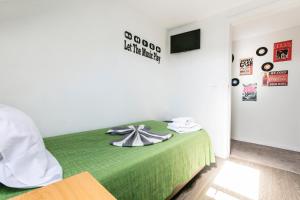 a bedroom with a bed with a green blanket at Guest House Porto Clerigus in Porto
