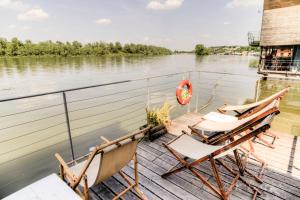 due sedie sedute su un molo vicino all'acqua di ArkaBarka 2- Floating Dream Rooms and Apartments a Belgrado