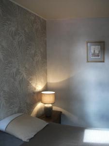 a bedroom with a bed and a lamp on a wall at L'Eldorado in Courseulles-sur-Mer