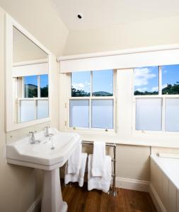 a white bathroom with windows and a sink at The Loch Lomond Arms Hotel in Luss