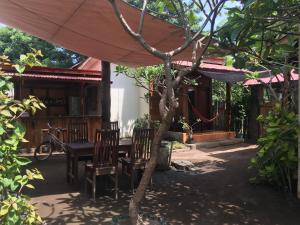 a patio with a table and chairs under an umbrella at The Joe Bungalow in Gili Trawangan