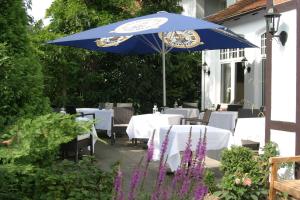 une terrasse avec des tables et un parasol bleu dans l'établissement Landhaus Bode, à Travemünde