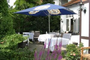 un patio con mesas y una sombrilla azul en Landhaus Bode, en Travemünde