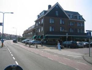 une femme traversant une rue devant un bâtiment dans l'établissement Hotel de Admiraal, à Noordwijk aan Zee