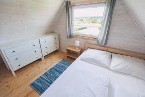 a bedroom with a white bed and a window at Domki Letniskowe Skandynawia in Ustka