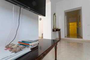 ein Wohnzimmer mit einem Tisch mit Büchern und einem TV in der Unterkunft Appartamento Piazza Pretoria in Palermo