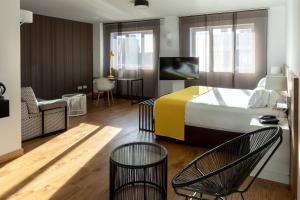 a bedroom with a bed and two chairs and a table at Rafaelhoteles Atocha in Madrid +26 photos