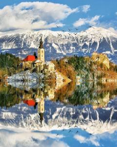 a reflection of a church in the water with mountains at Apartments and Rooms Tavcar in Bled