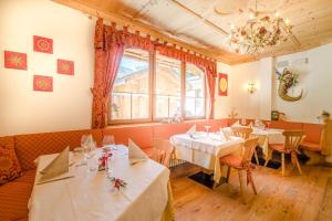 restauracja ze stołami i krzesłami oraz żyrandolem w obiekcie Pineta Pastry Hotel w mieście Rocca Pietore