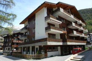 - un bâtiment avec balcon sur le côté d'une rue dans l'établissement Myzermatt Monazit, à Zermatt