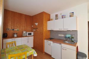 a kitchen with white cabinets and a table in it at Weinhotel Lenz in Pünderich