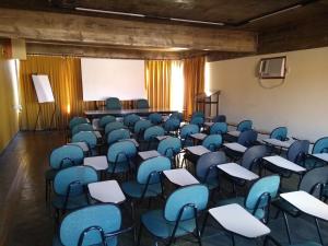an empty room with blue chairs and desks in it at Alfenas Palace Hotel in Alfenas