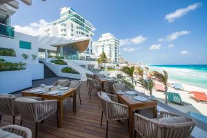 een restaurant met tafels en stoelen op een balkon met uitzicht op het strand bij Oleo Cancun Playa All Inclusive Resort in Cancun