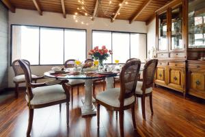 a dining room with a table and chairs and windows at Penthouse Lodge B&B in Quito