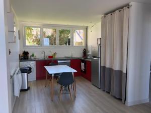 eine Küche mit roten Schränken und einem Tisch mit Stühlen in der Unterkunft Villa Sainte Marguerite in Wimereux