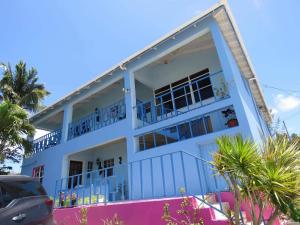 a white building with blue balconies and palm trees at Ellen Bay Cottages in Saint Philips