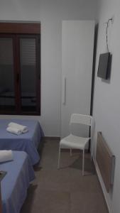 a room with two beds and a chair and a television at Hospederia Gomis 26 in Ontinyent